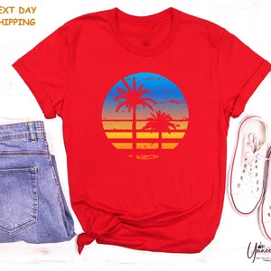 a red shirt with a sunset and palm trees on it