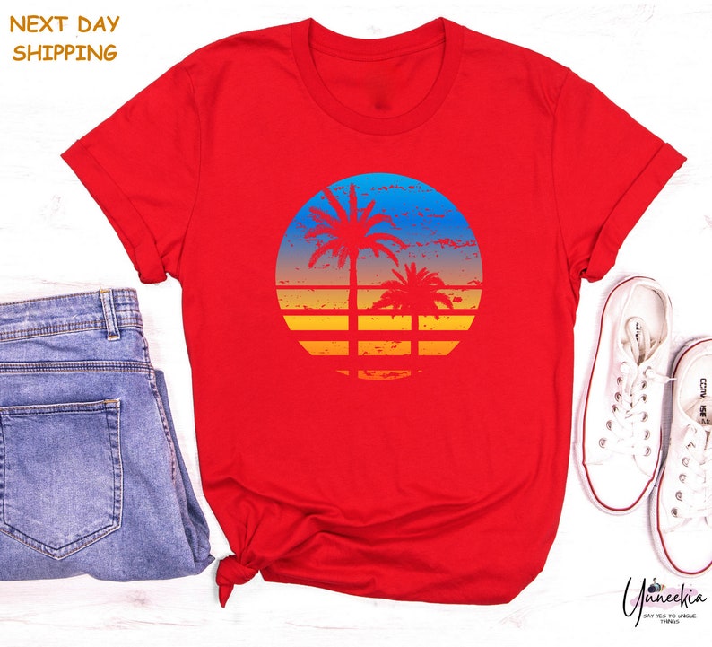 a red shirt with a sunset and palm trees on it