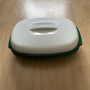 Könnte beinhalten: Ein weiß-grüner Lebensmittelbehälter mit Griff am Deckel. Der Behälter hat eine rechteckige Form mit abgerundeten Kanten. Der Boden ist grün, der Deckel weiß.