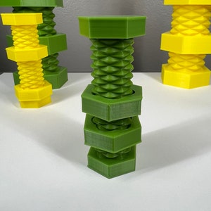 May include: A stack of green plastic nuts and bolts. The nuts and bolts are hexagonal in shape and have a threaded design.