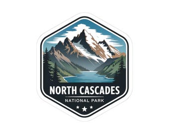 May include: A sticker featuring a mountain range with snow-capped peaks, a lake, and evergreen trees. The sticker is in a hexagonal shape with the text "NORTH CASCADES NATIONAL PARK" and three stars.