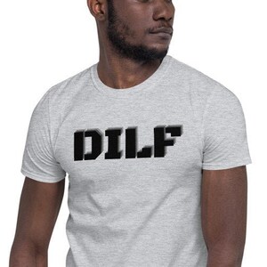 Puede incluir: Una camiseta gris con la palabra "DILF" impresa en letras negras.