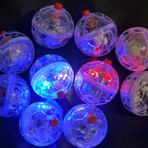 May include: Ten clear plastic balls with a soccer ball design. Each ball has a red button on top and lights up with blue and red LED lights.