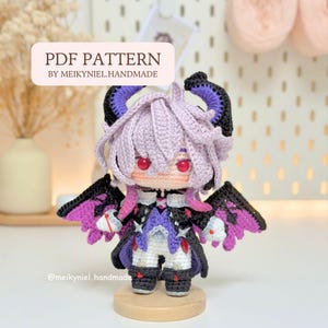 Könnte beinhalten: Eine handgefertigte Häkelpuppe mit Fantasy-Thema. Die Puppe hat lila Haare, rote Augen und schwarze und lila Flügel. Die Puppe trägt ein schwarzes und lila Outfit. Der Text "PDF PATTERN BY MEIKYNIEL.HANDMADE" ist auf dem Bild zu sehen.