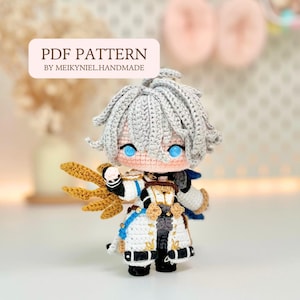 May include: A handcrafted crochet doll with grey hair and blue eyes, dressed in a white and black outfit with gold detailing. The doll features an intricate design and holds a gold wing. The image includes the text "PDF PATTERN BY MEIKYNIEL.HANDMADE."