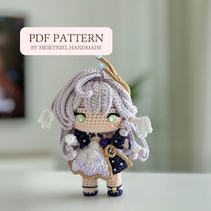 May include: Crochet amigurumi doll with purple hair, a white dress, and a gold crown. The doll has green eyes and a cute expression. The doll is standing on a white surface. PDF PATTERN BY MEIKYNIEL.HANDMADE