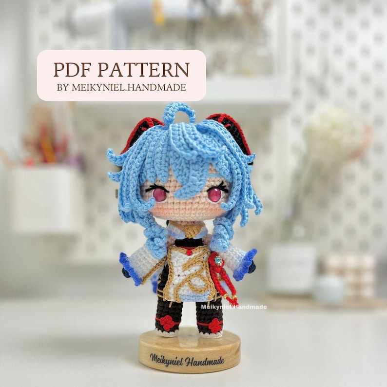 May include: Crochet amigurumi pattern for a blue-haired anime character with red accents. The pattern is available as a PDF download. The character is standing on a wooden base with the text "Meikyniel Handmade".