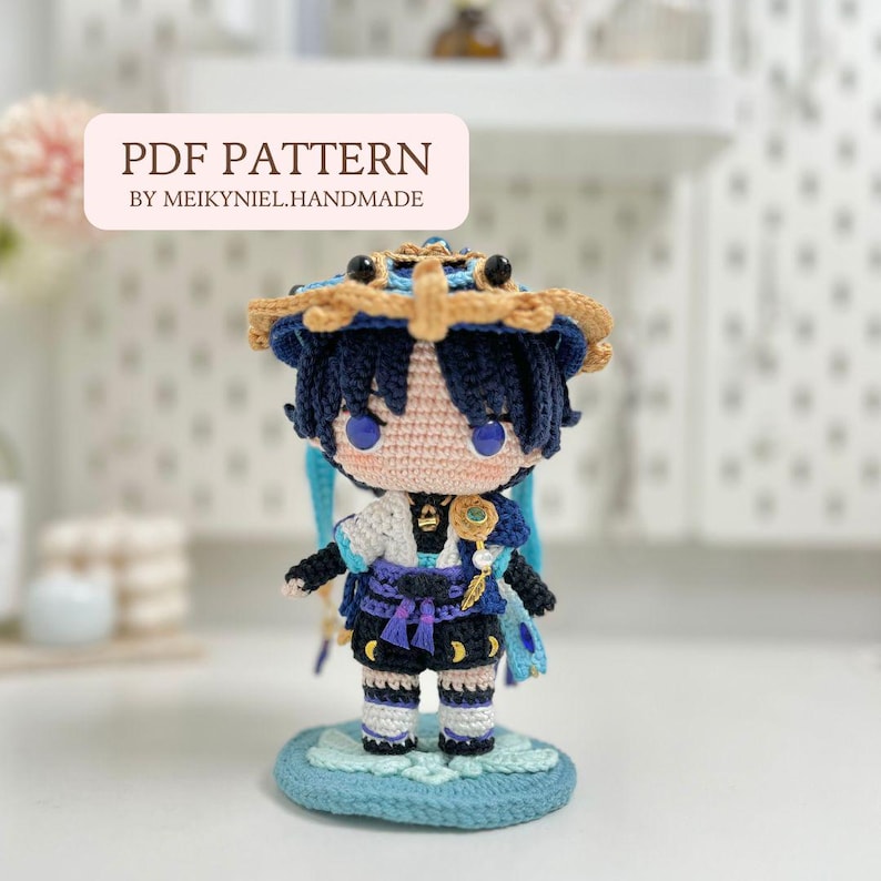 Op de afbeelding: Haak amigurumi patroon voor een blauw en gouden personage met een kroon, die een sleutel vasthoudt. Het patroon heet "PDF PATTERN BY MEIKYNIEL.HANDMADE".