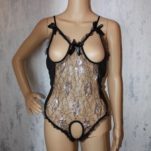 May include: Black lace bodysuit with a silver shimmer and a cutout design. The bodysuit has a low neckline and a plunging back.