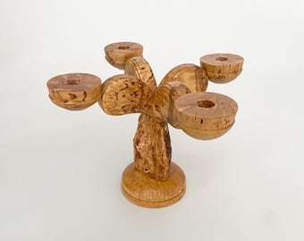 May include: A wooden candle holder with five candle cups. The holder is carved in a tree-like shape with a natural wood finish.
