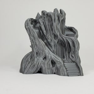 May include: A 3D printed gray resin model of a tree house with a detailed, textured exterior and a door with a tree design. The house has two sets of stairs leading up to the top.