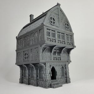 Könnte beinhalten: Ein graues 3D-gedrucktes Modell eines mittelalterlichen Gebäudes mit einem Strohdach, mehreren Fenstern und einem Steinsockel.