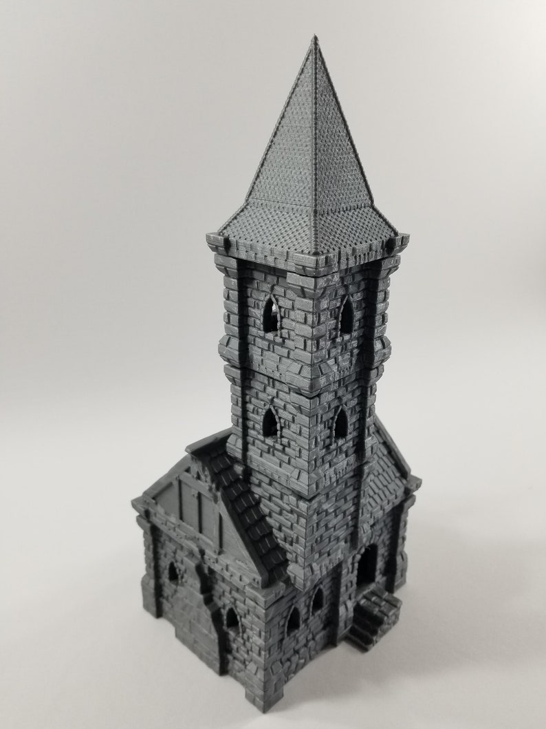 May include: A gray 3D printed miniature of a stone tower with a pointed roof and small windows. The tower is a building model for tabletop games or miniature painting.