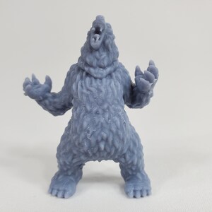 May include: A grey 3D printed figurine of a bear standing on all fours with its mouth open in a roar. The bear has a textured surface that resembles fur.
