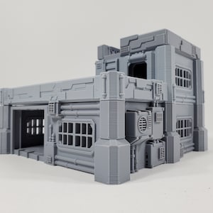 Könnte beinhalten: Ein graues 3D-gedrucktes Modell eines futuristischen Gebäudes mit einem Garagentor, Fenstern und Rohren. Das Gebäude besteht aus mehreren Ebenen und hat ein detailliertes Design.