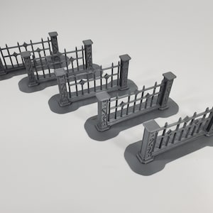 May include: Four gray metal fence sections with decorative details. Each section has two posts and a series of vertical bars with pointed tops.