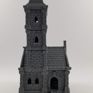 May include: A gray 3D printed miniature of a stone church with a tall tower and a small entrance. The church has a pointed roof and several windows.