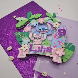 Peut inclure: Décoration de gâteau d'anniversaire violette et rose pailletée à plusieurs niveaux, avec les personnages Stitch et Angel. La décoration comprend le nom "Lilia", une planche de surf avec le chiffre 9 et des fleurs tropicales. Le texte "Mercreation'Elle" est également visible.