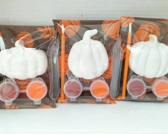 May include: Three sets of pumpkin painting kits. Each kit includes a white ceramic pumpkin, two small paint pots, a paintbrush, and a brown and orange patterned paper bag.