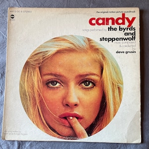 May include: Vintage vinyl record album cover for the soundtrack of "Candy." The cover features a woman's face in a circular design, with the title in red and the artists' names. The album is a stereo recording.