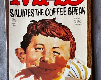May include: The cover of MAD Magazine, issue No. 222 from April 1981, features a cartoon illustration of a boy with coffee spilling on his face. The magazine's title, "MAD," is in large red letters. The cover also includes the text "SALUTES THE COFFEE BREAK."