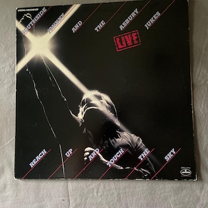 May include: A square vinyl record album cover featuring a black and white photograph of a performer reaching toward a bright light. The text reads Southside Johnny and the Asbury Jukes Live, Reach Up and Touch the Sky, and Special 2-Record Set.
