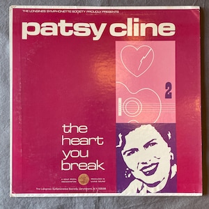 May include: A vintage vinyl record album cover for Patsy Cline's "The Heart You Break." The cover is primarily magenta with white text, featuring a portrait of Cline and a graphic of a guitar and heart.