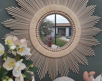 Décoration soleil. Miroir rond en bois naturel cerné de raphia tressé, de cordes de lin et d'un collier de perles