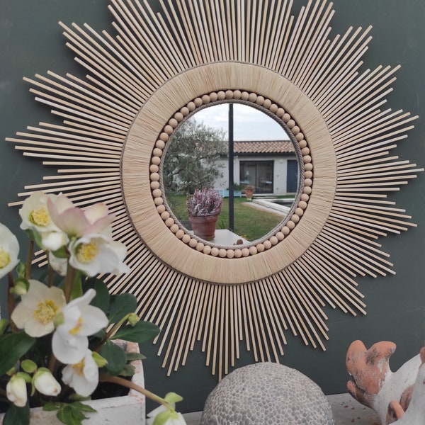 Décoration soleil. Miroir rond en bois naturel cerné de raphia tressé, de cordes de lin et d'un collier de perles