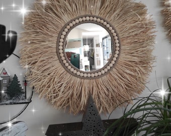 Ronde spiegel van natuurlijk raffia omgeven door touwen en natuurlijke houten kralen