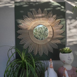 Round mirror in natural wood surrounded by concentric circles in a very trendy and floral material