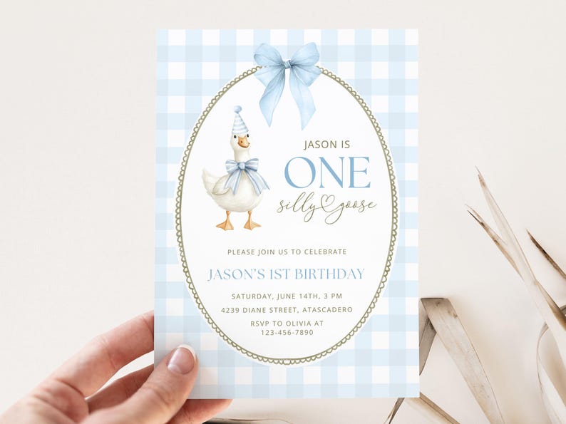 May include: A rectangular birthday invitation card featuring a light blue and white gingham pattern. The center displays an oval frame with a blue bow, a goose wearing a party hat and bow, and the text: JASON IS ONE SILLY GOOSE, PLEASE JOIN US TO CELEBRATE JASON'S 1ST BIRTHDAY, SATURDAY, JUNE 14TH, 3 PM, 4239 DIANE STREET, ATASCADERO, RSVP TO OLIVIA AT 123-456-7890.