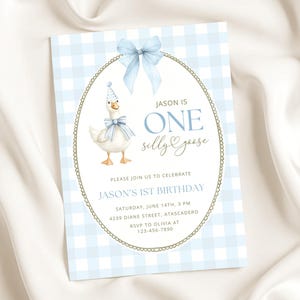 May include: A rectangular invitation card with a light blue and white gingham background. It features a white oval frame with a gold border and a light blue bow at the top. Inside, a goose wears a party hat and bow, with text reading JASON IS ONE silly goose, JASON'S 1ST BIRTHDAY, and event details.