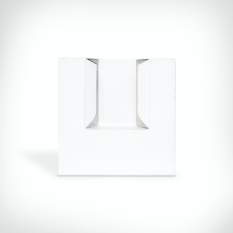 May include: White cardboard box with two cut-out slots on the front. The box is designed to hold a product, such as a bottle or a candle.