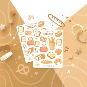 Puede incluir: Dos hojas de pegatinas con ilustraciones temáticas de pan, que incluyen tostadas sonrientes, pretzels y una tostadora. El texto "Let's Get This Bread!" está presente. Las pegatinas están sobre un fondo beige y blanco con elementos decorativos.