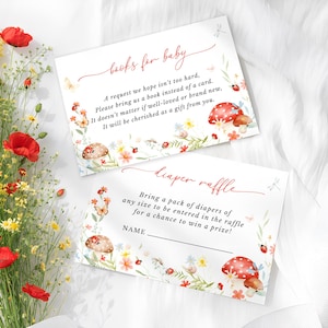 May include: Two baby shower invitation cards with floral and mushroom illustrations. One card reads "books for baby" and the other reads "diaper raffle". A bouquet of red poppies and yellow flowers is in the background.