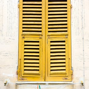 Könnte beinhalten: Gelbe Holzläden, die ein Fenster verschließen, mit einer Wäscheleine darunter.