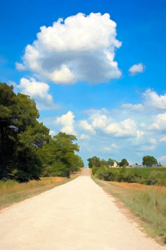 Rural Kansas gravel road with clouds and a farm.