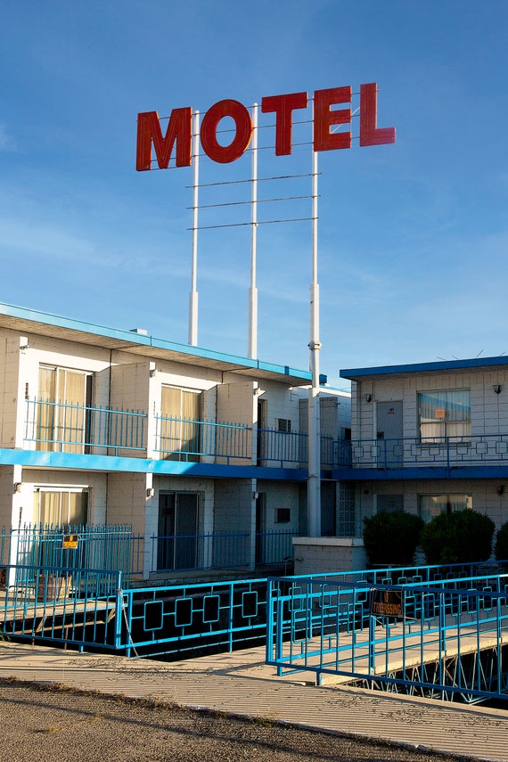American motel in daylight with sign on a tall pole.