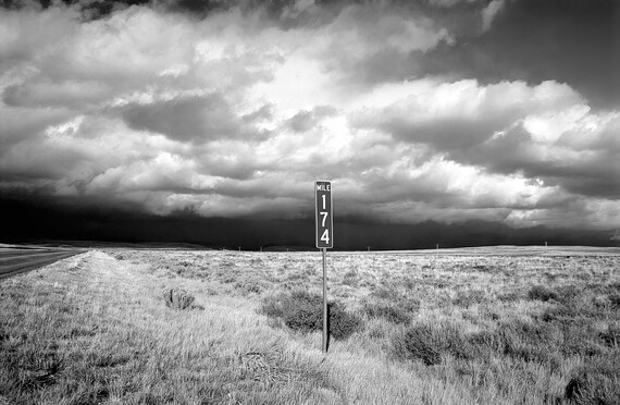 Remote US highway with mileage marker and storm coming.