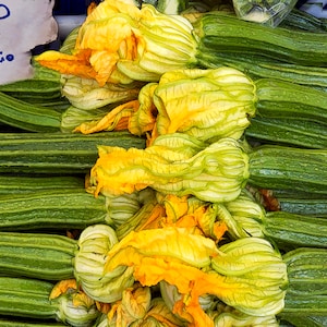 Photo of flowering zucchini for sale at outdoor market in Italy.