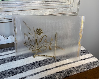 May include: Rectangular clear glass serving tray with a textured surface and gold floral design. The tray has gold wheat stalk accents on the edges and a gold floral arrangement in the center. The tray is supported by a gold metal stand.