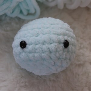 May include: A light blue crocheted plush toy with black button eyes.