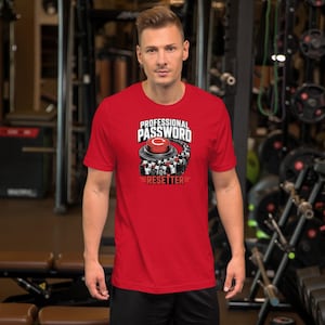 May include: A red short-sleeved t-shirt featuring a graphic print of a large red button with a white circular arrow icon. Above the button is the text "PROFESSIONAL PASSWORD" and below it is the text "RESETTER" in bold white and black lettering.