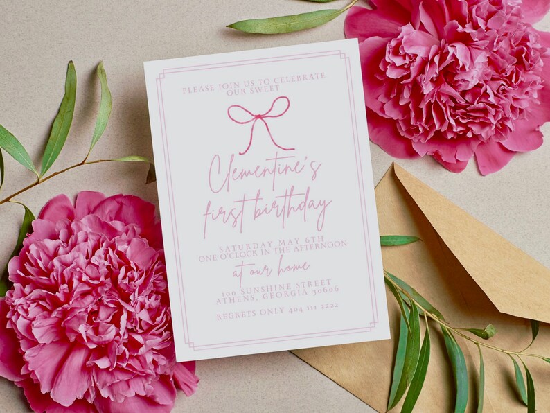 Op de afbeelding: Een witte uitnodigingskaart met roze tekst en een roze strik. De tekst luidt: "We nodigen u graag uit om onze lieve Clementine's eerste verjaardag te vieren. Zaterdag 6 mei, om 13:00 uur 's middags bij ons thuis, 201 Sunshine Street, Athens, Georgia 30606. Alleen afmeldingen via 404 111 2323."
