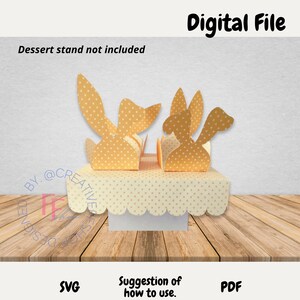 May include: A digital file for a 3D papercraft bunny cupcake stand. The stand is made of yellow paper with white polka dots and features four bunny heads. The stand is designed to hold cupcakes or other small treats. The image shows a suggestion of how to use the stand.