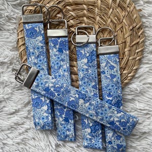 May include: Five blue and white floral patterned keychains with silver key rings.