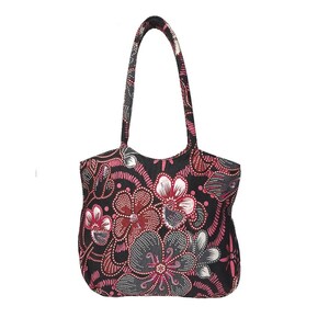 May include: A black tote bag with a floral pattern in shades of red, pink, gray, and white. The bag has two handles and a rounded shape. The floral design is detailed with dotted accents.