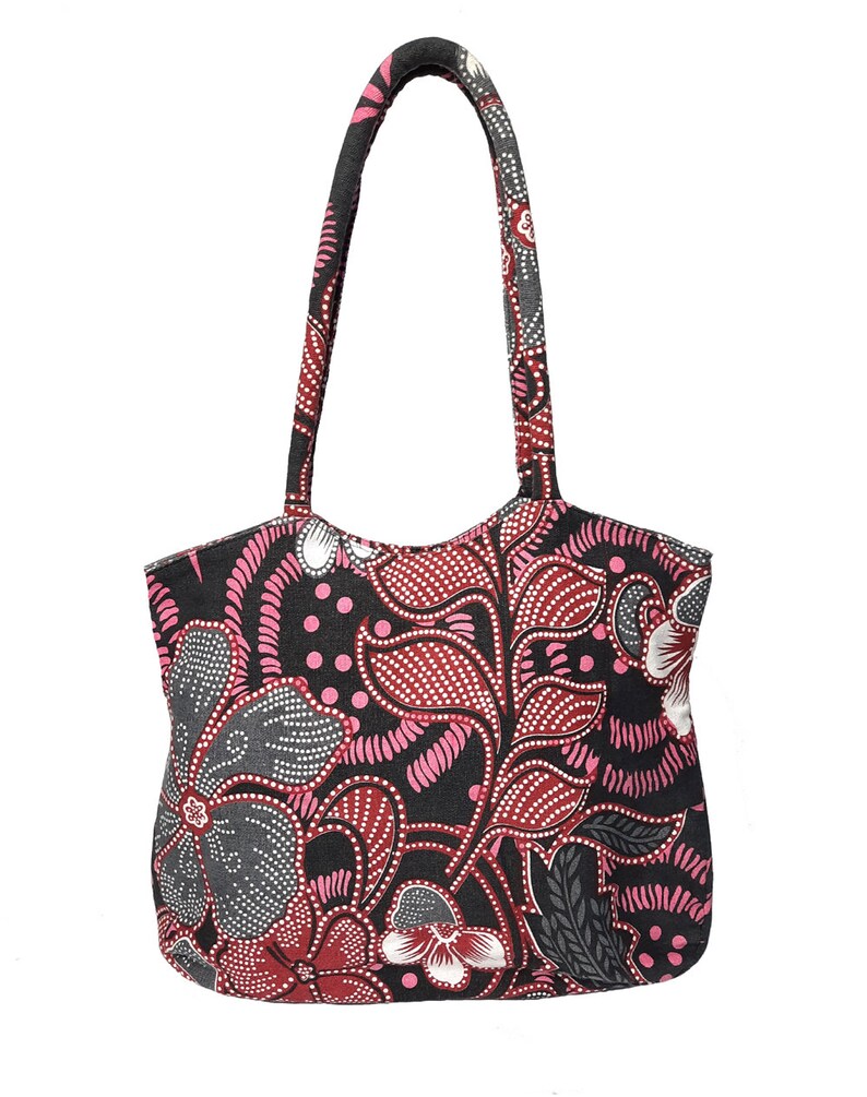 May include: A tote bag with a floral pattern in shades of pink, red, gray, and white on a black background. The bag has two handles and a rounded top. The floral design is intricate and detailed, with a batik-style appearance.