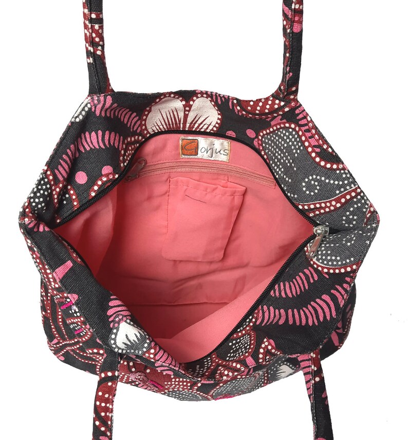 May include: Open tote bag with a black background and a pink and white floral pattern. The interior is a solid pink color with a small pocket. The bag has two handles and a zipper closure. The tag says "Gorjus".